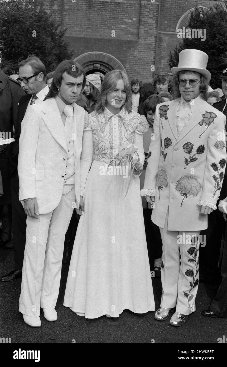 Elton John (right) pictured here as best man to his songwriting partner Bernie Taupin. Bernie marries 19 year old American student Maxine Feibelman on Saturday 27th March 1971 at  Holy Rood Catholic Church, in Market Rasen, Lincolnshire.  Best man Elton wears a white suit embroided with red and yellow roses, and a white silk top hat. All made in Los Angeles, by the same tailer who has designed suits for Elvis Presley. (Tailer is named in captioned but writing difficult to make out)  Bride Maxine, wears a full length traditional gown in white with old gold irises embroided on the bodice.  Groom Stock Photo