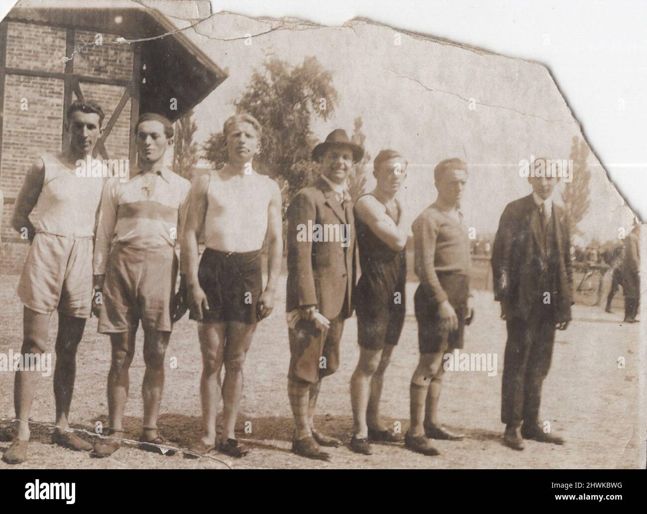 an antique survival  damaged monochrome photograph about sportsmen whose are standing in line with them coaches at the 1900s. Period: 1900s, Source: original photograph. ADDITIONAL-RIGHTS-CLEARANCE-INFO-NOT-AVAILABLE Stock Photo