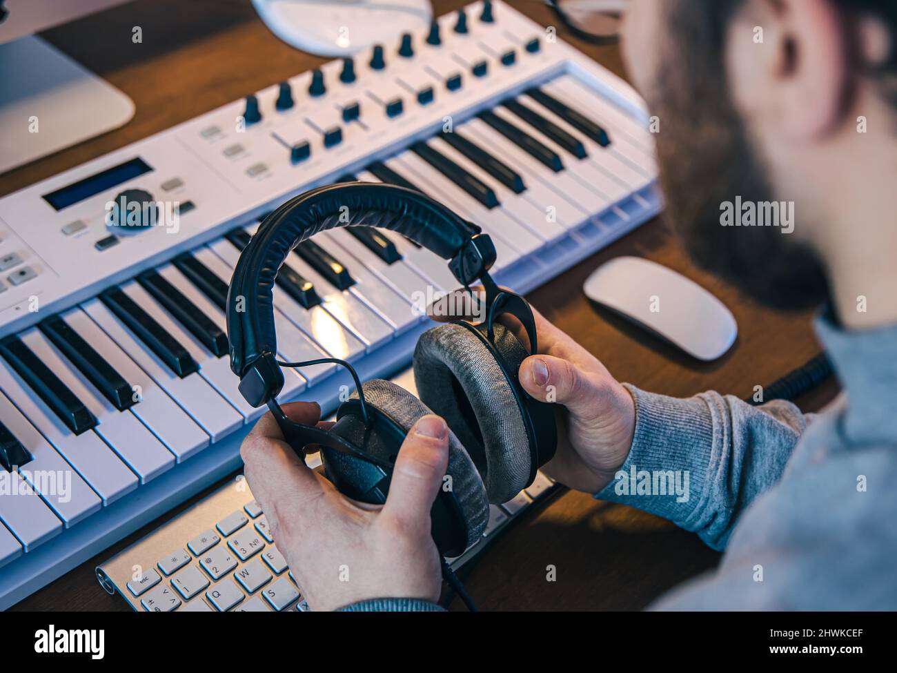 Male musician creates music using computer and keyboard, musician