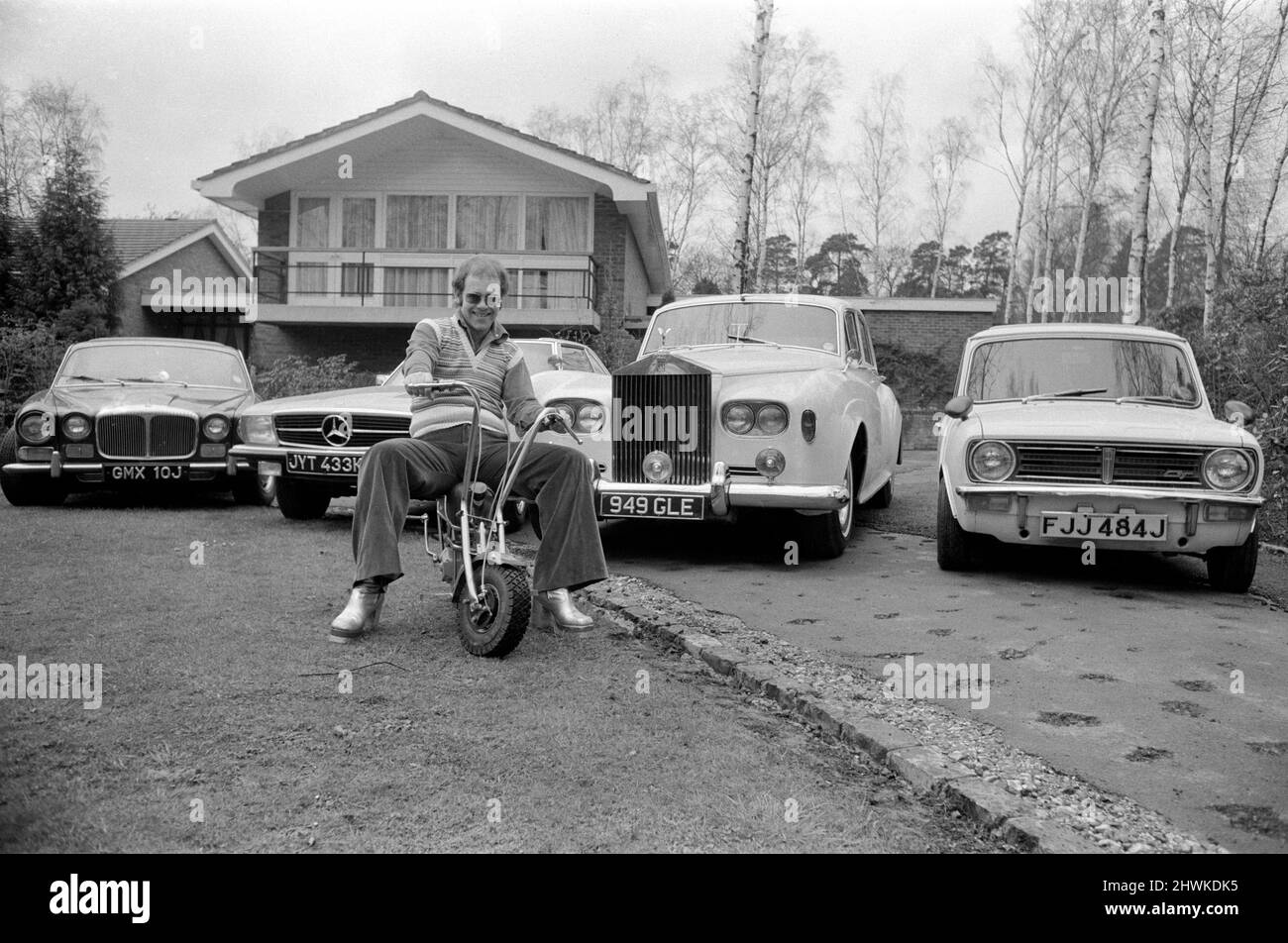 Elton John pictured at his home, sitting on a small motorbike in front of four of his cars.His cars include a Mercedes (2nd left) and a white Rolls Royce (3rd left)  Picture taken 4th April 1972 Stock Photo