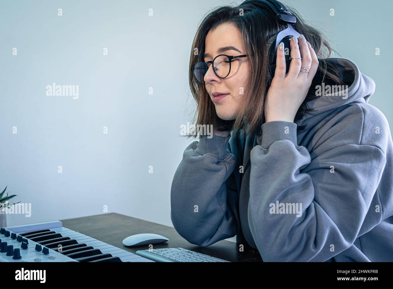 A young woman creates music using a musical keyboard and a computer ...