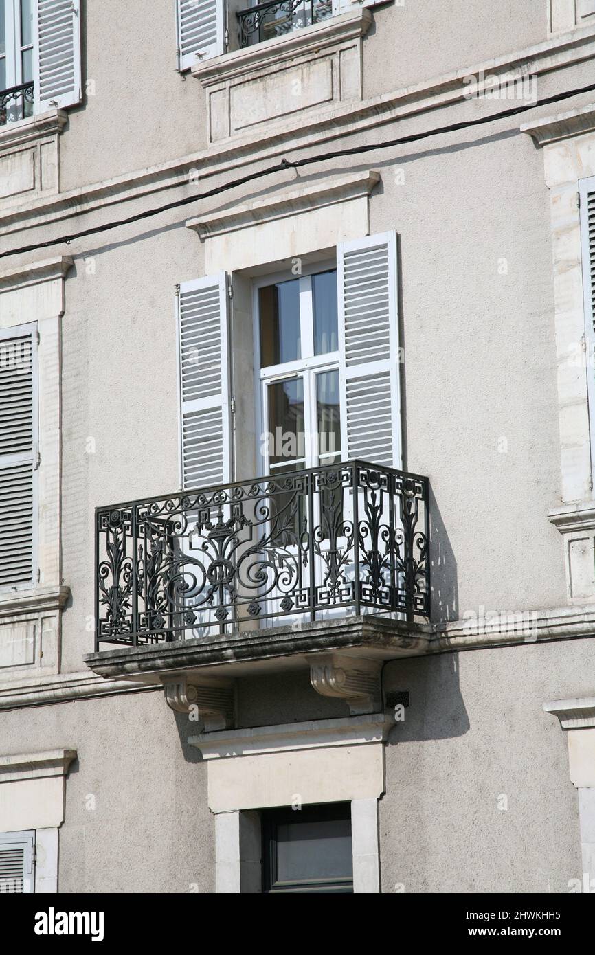 Typical French apartment building balcony, with cast iron decorations and louvered shutters to block the afternoon sun Stock Photo