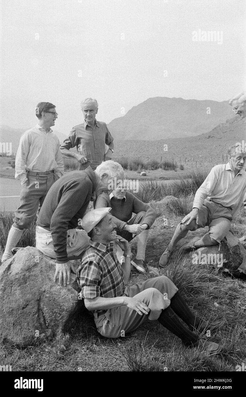 Everest Men reunion at The Pen-y-Grwd Training base at Capel Curig, north Wales.  26th May 1973 It is 20 years on from the 1953 Everest Climb, with this reunion in Wales in May 1973  Picture features : Lord Hunt, ( white hair, dark top, sitting on rock looking down talking to Sherpa Tensing). Sherpa Tensing Norgay (Sherpa Tenzing Norgay) is in the chequered shirt and cap sitting on the ground in the forefront looking up), The other men here are no id'd  Note, Sir Edmund Hillary was not able to make this reunion.  Picture taken 26th May 1973 Stock Photo