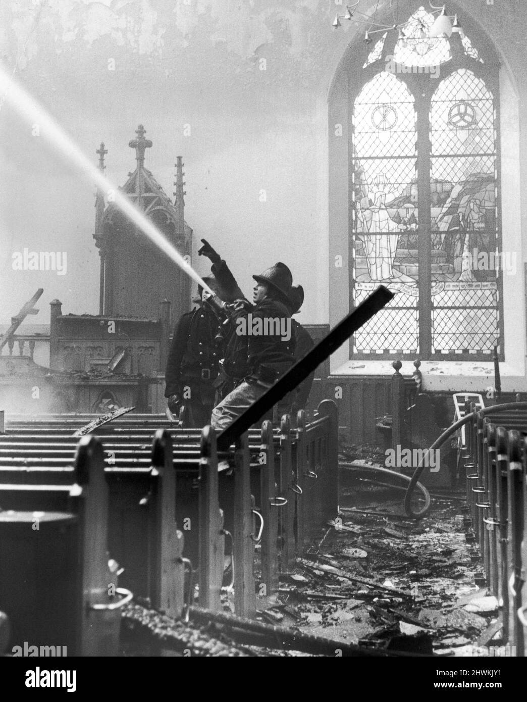 Fire at Morningside Baptist Church, December 1973. Firemen battle against the flames, amid silent pews overlooked by stained glass window. An eectrical fault in the gallery of the 100 year old church is thought to have started the blaze. Stock Photo