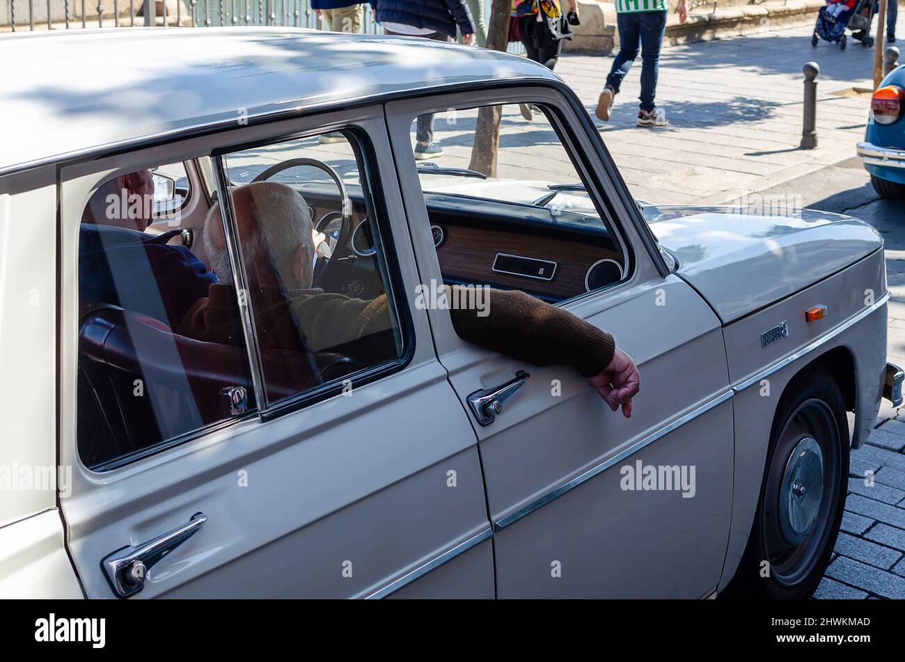 Old man with his arm out of a classic car. White Renault 8. Stock Photo