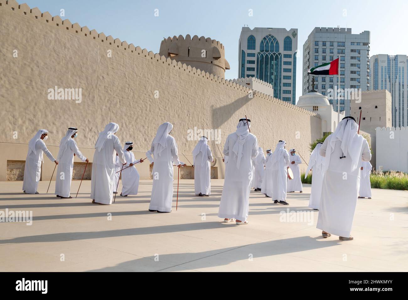 ABU DHABI, UAE - MAY 14, 2021: Traditional Emirati male Al Ayalah dance at Al Hosn Festival with UAE flag at the background Stock Photo
