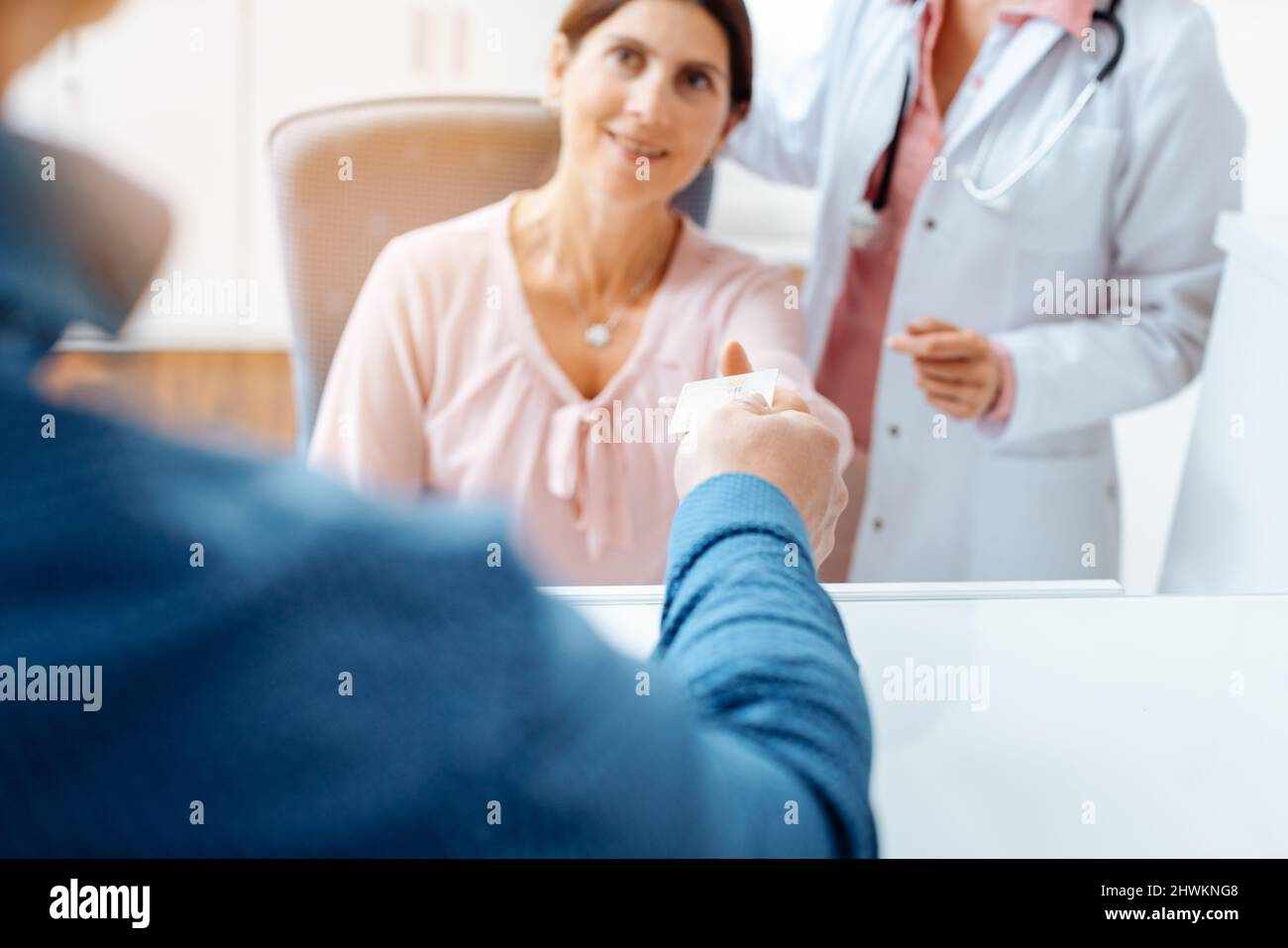 Patient giving electronic health card at front desk of doctor's office Stock Photo
