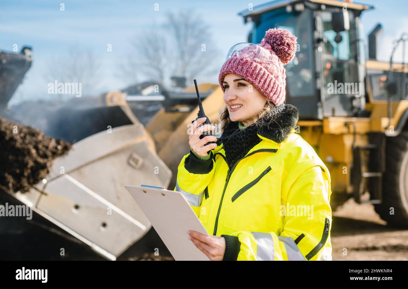 Woman with walkie talky on compost facility dispatching deliveries Stock Photo