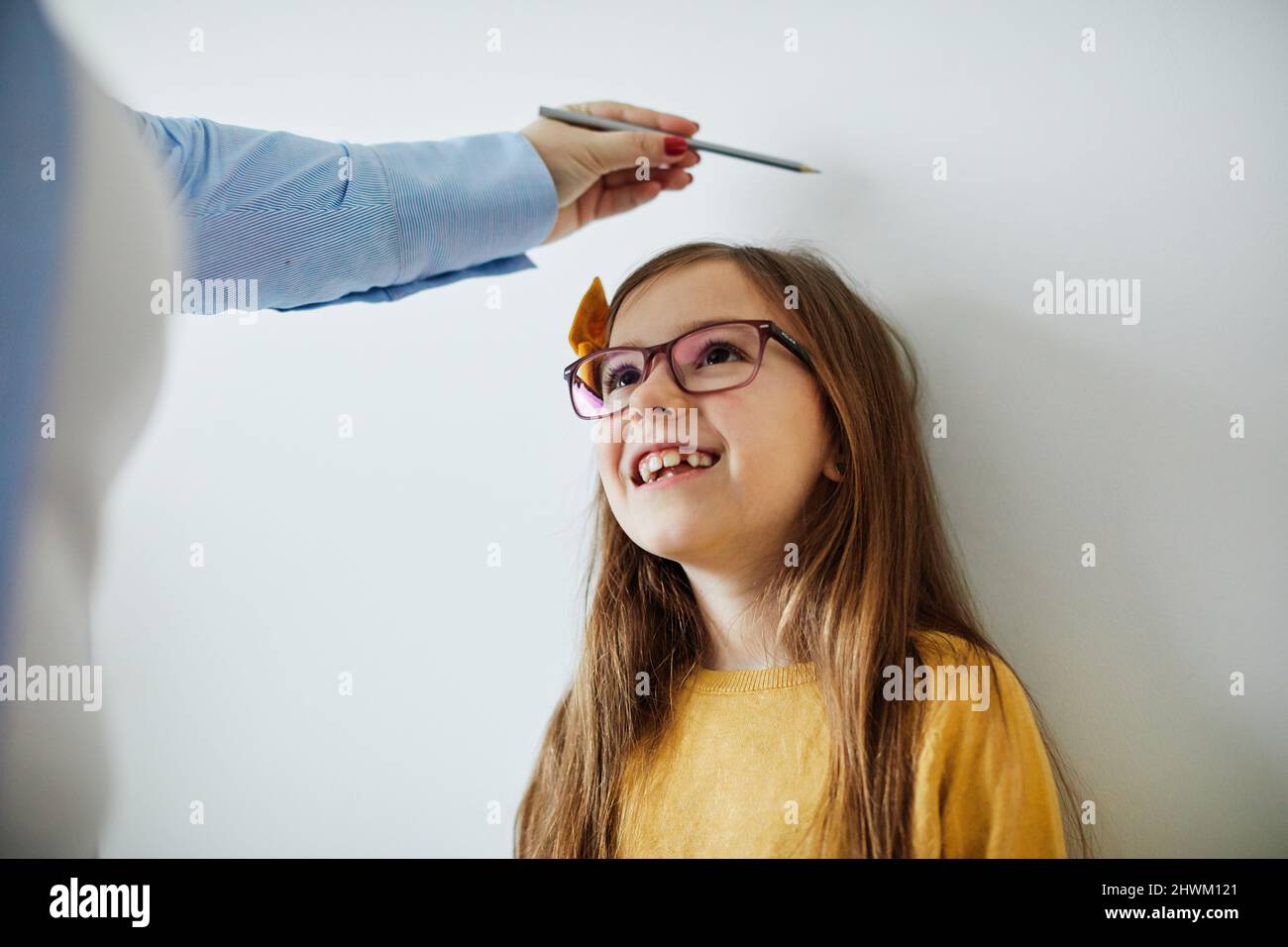 daughter mother measuring height growth childhood tall child heigth kid wall cute Stock Photo