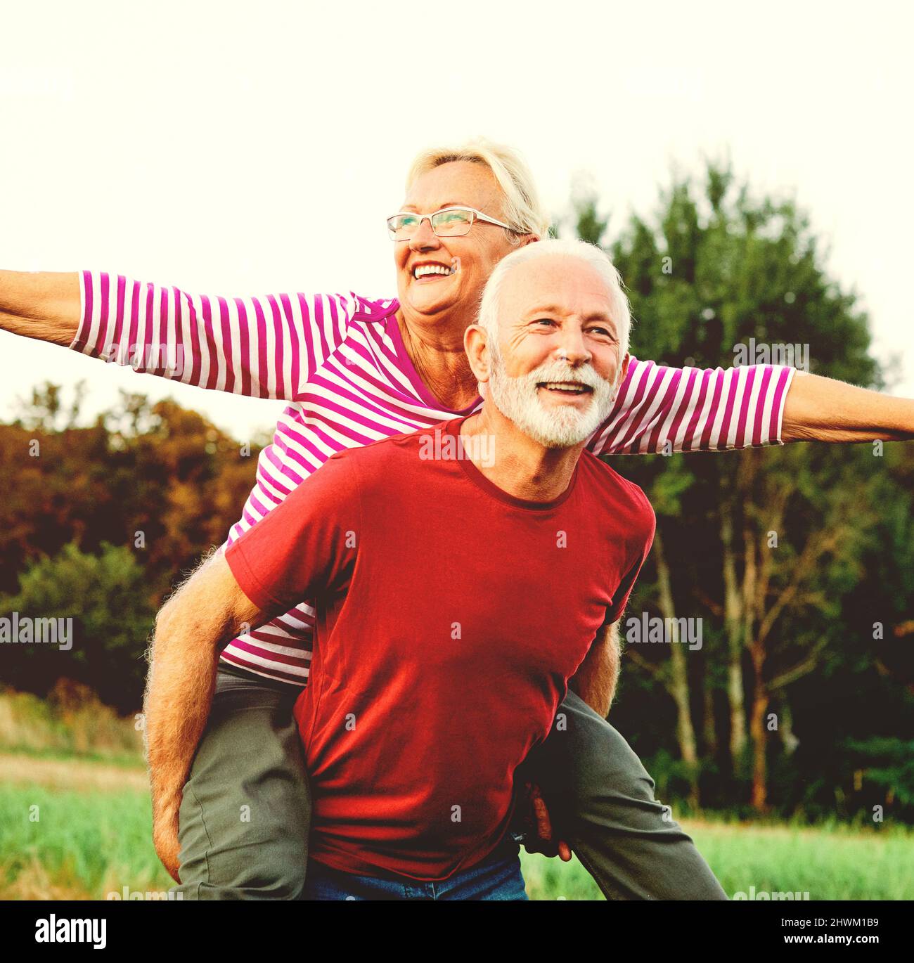 woman man outdoor senior couple happy lifestyle retirement together smiling love piggyback active mature Stock Photo