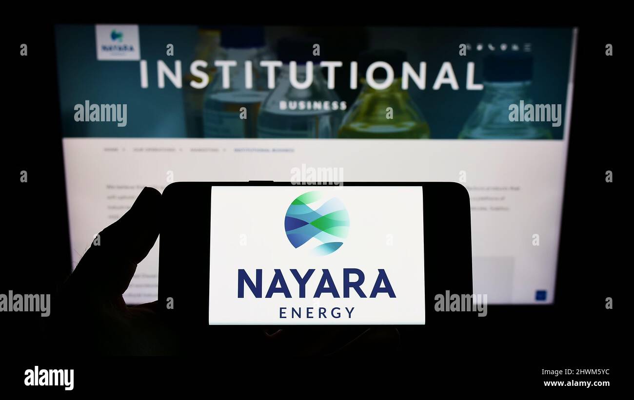 Person holding smartphone with logo of Indian petroleum company Nayara Energy Limited on screen in front of website. Focus on phone display. Stock Photo