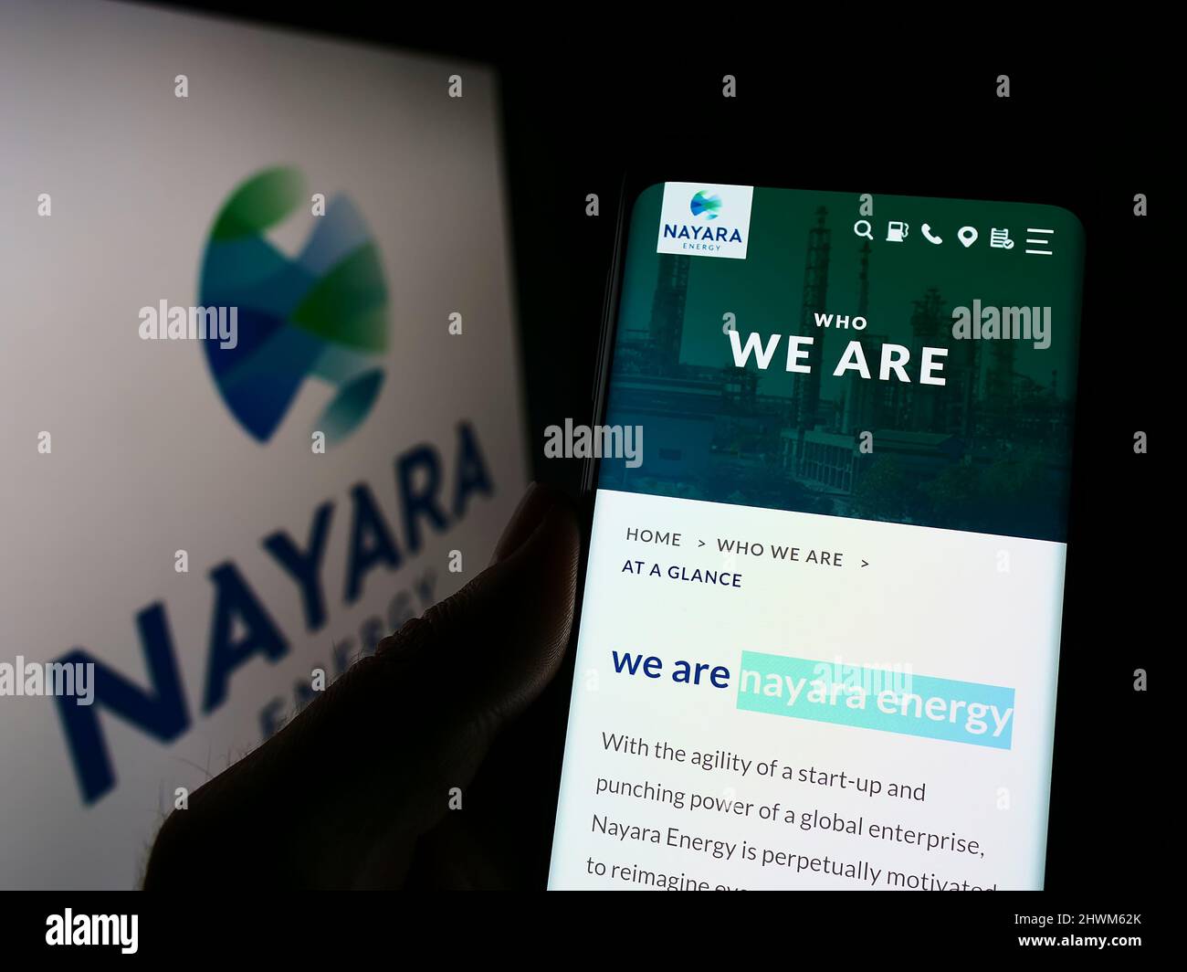 Person holding smartphone with website of Indian petroleum company Nayara Energy Limited on screen with logo. Focus on center of phone display. Stock Photo