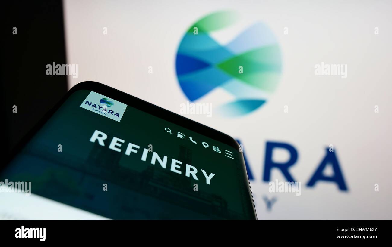 Mobile phone with webpage of Indian petroleum company Nayara Energy Limited on screen in front of logo. Focus on top-left of phone display. Stock Photo