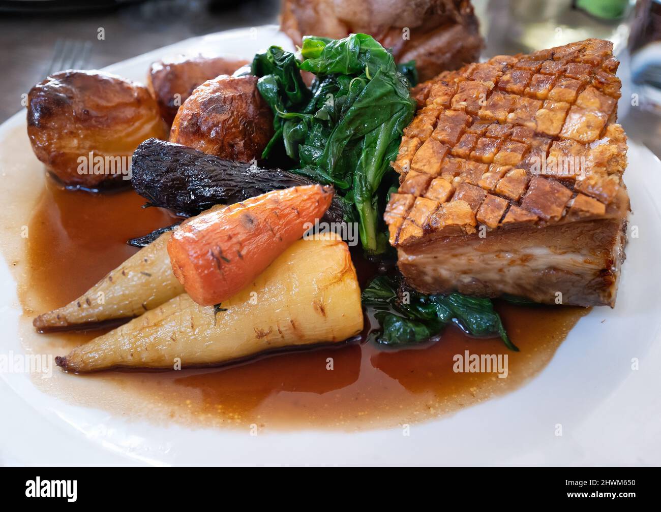 Roast pork Sunday lunch meal. The pork has crispy skin crackling. The