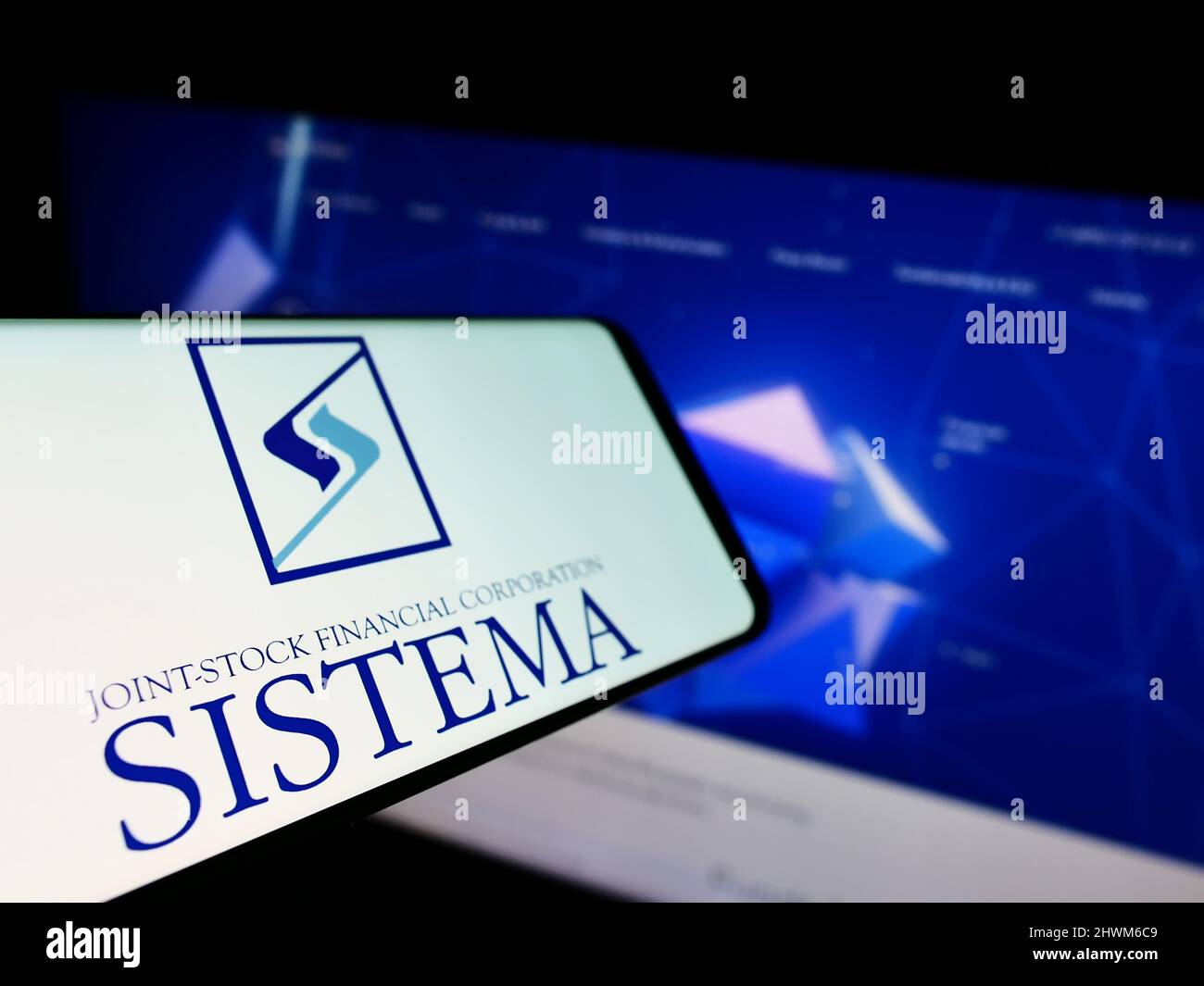 Mobile phone with logo of Russian conglomerate AFK Sistema PAO on screen in front of company website. Focus on center-left of phone display. Stock Photo