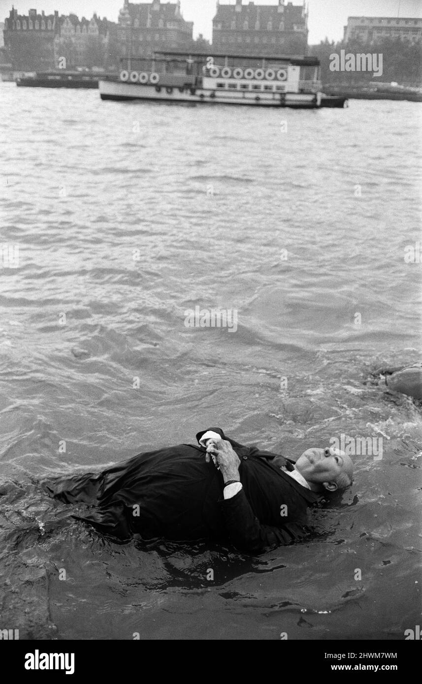 Bodies floated up and down the Thames alongside County Hall and no one batted an eye. Alfred Hitchcock hands on chest floated up and onlookers laughed, the sight of Mr Hitchcock walking around assured them it was not him in the river but a plastic model. Alfred and his team were on location for his latest film 'Frenzy', due out next Easter. 26th August 1971. Stock Photo