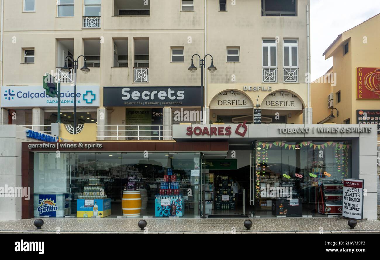 Retail outlets along the quayside in Vilamoura, Portugal including a  wine/spirit tobacco merchant, beauty salon and clothing shop Stock Photo