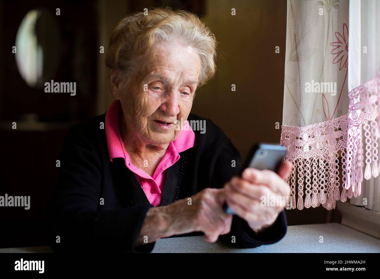 An old woman typing on the smartphone. Stock Photo