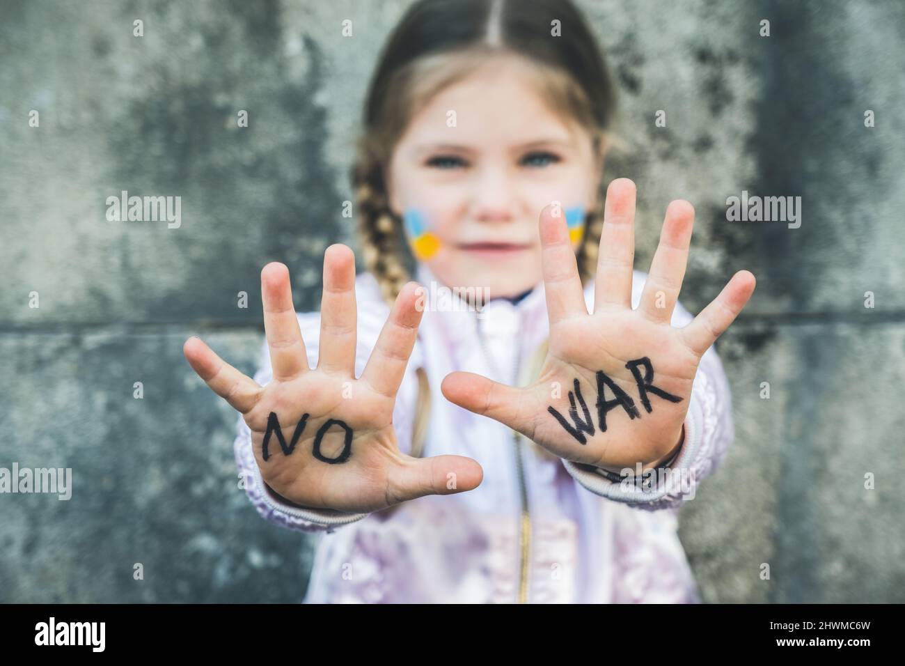 Beautiful and scared child inscription NO WAR on his hands. Russia's invasion of Ukraine, kids against the war Stock Photo