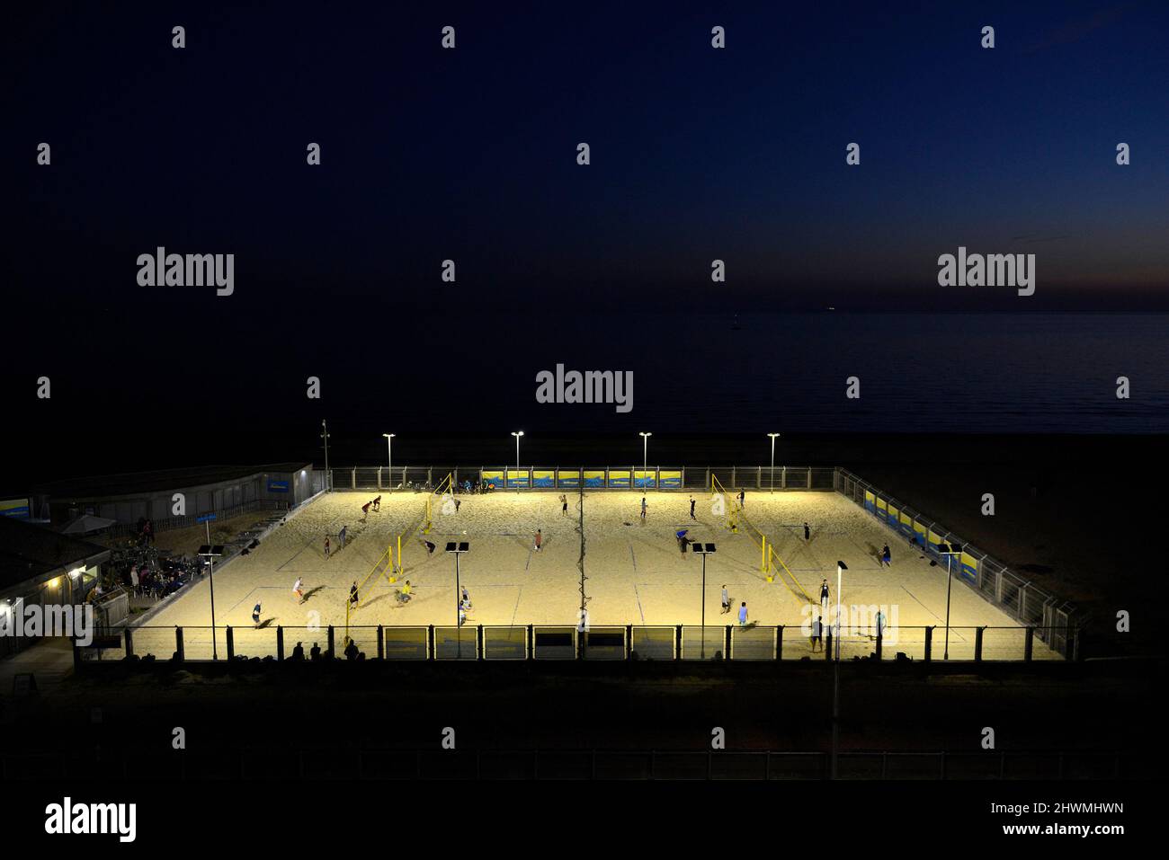 Busy beach volleyball courts on the seafront at Brighton, UK at night