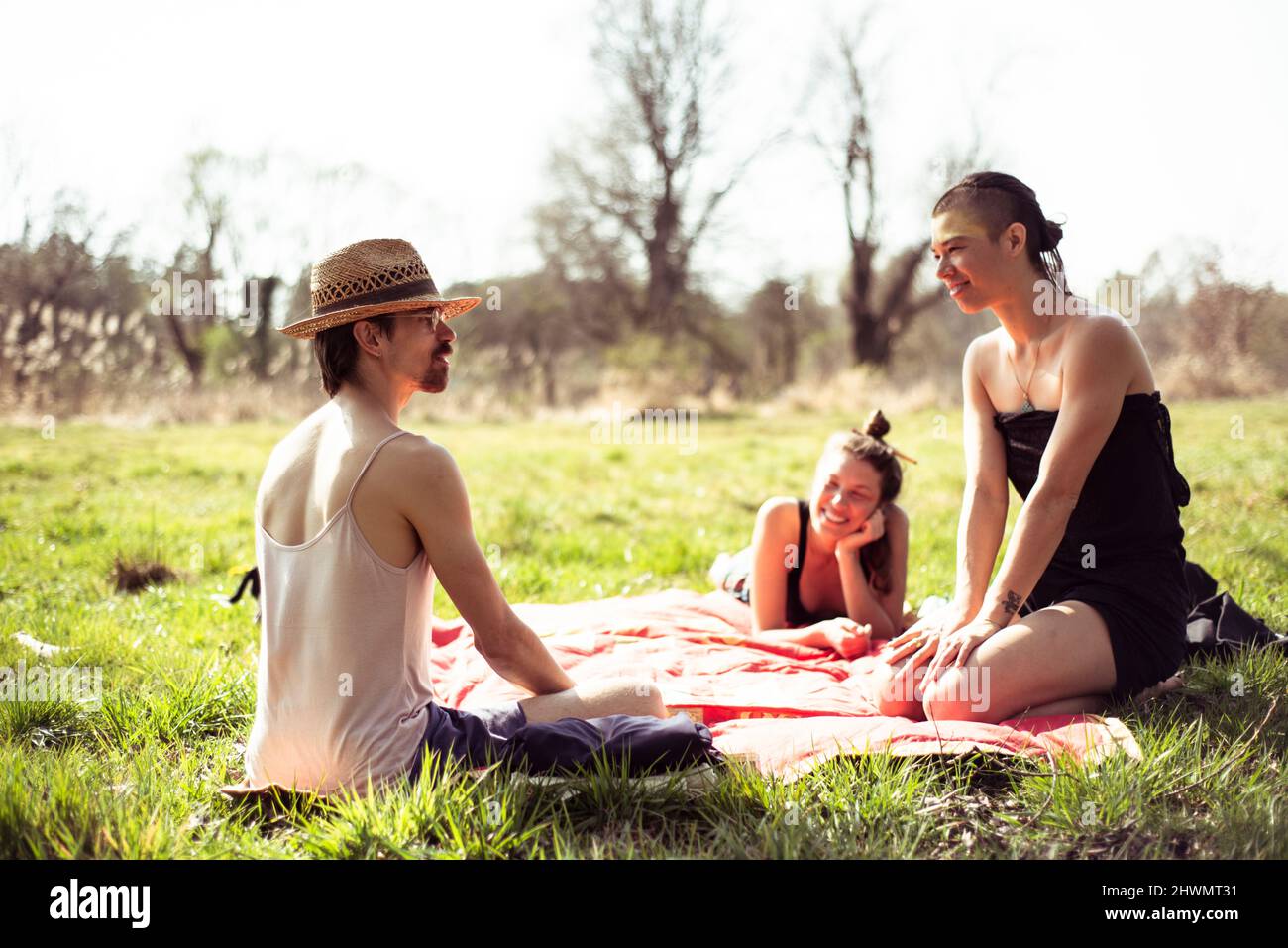non-binary friends relax at picnic on spring afternoon outdoors german Stock Photo