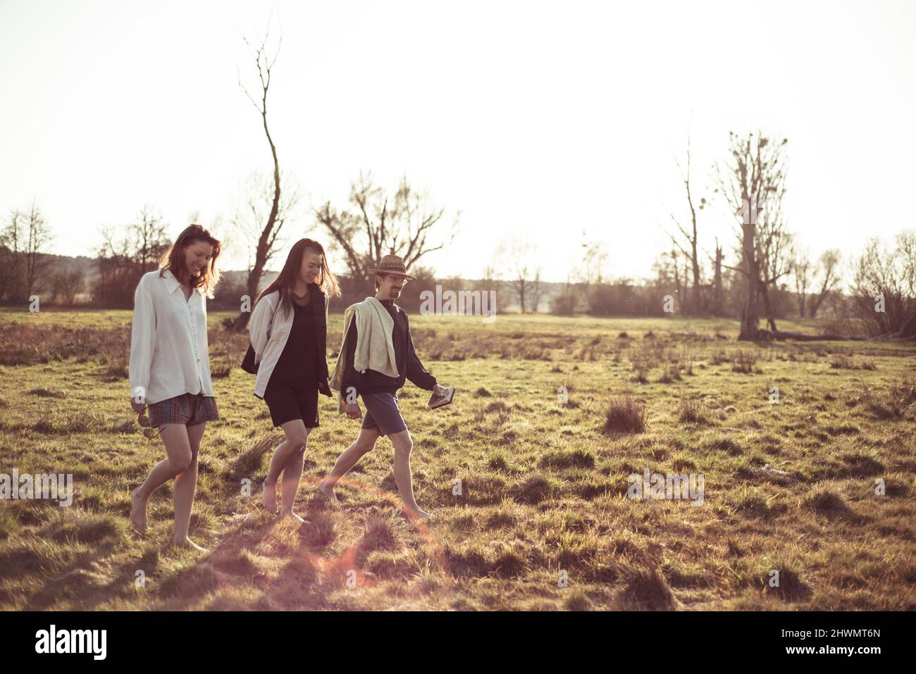 Young alternative friends walk barefoot in spring afternoon sunset Stock Photo