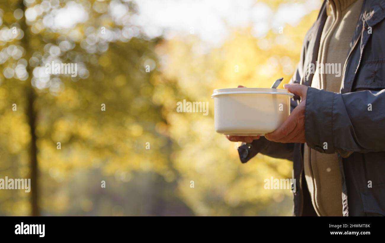 Person holding a plastic bowl with nutritious food prepared by volunteers who help homeless, poor, people in need. High quality photo Stock Photo