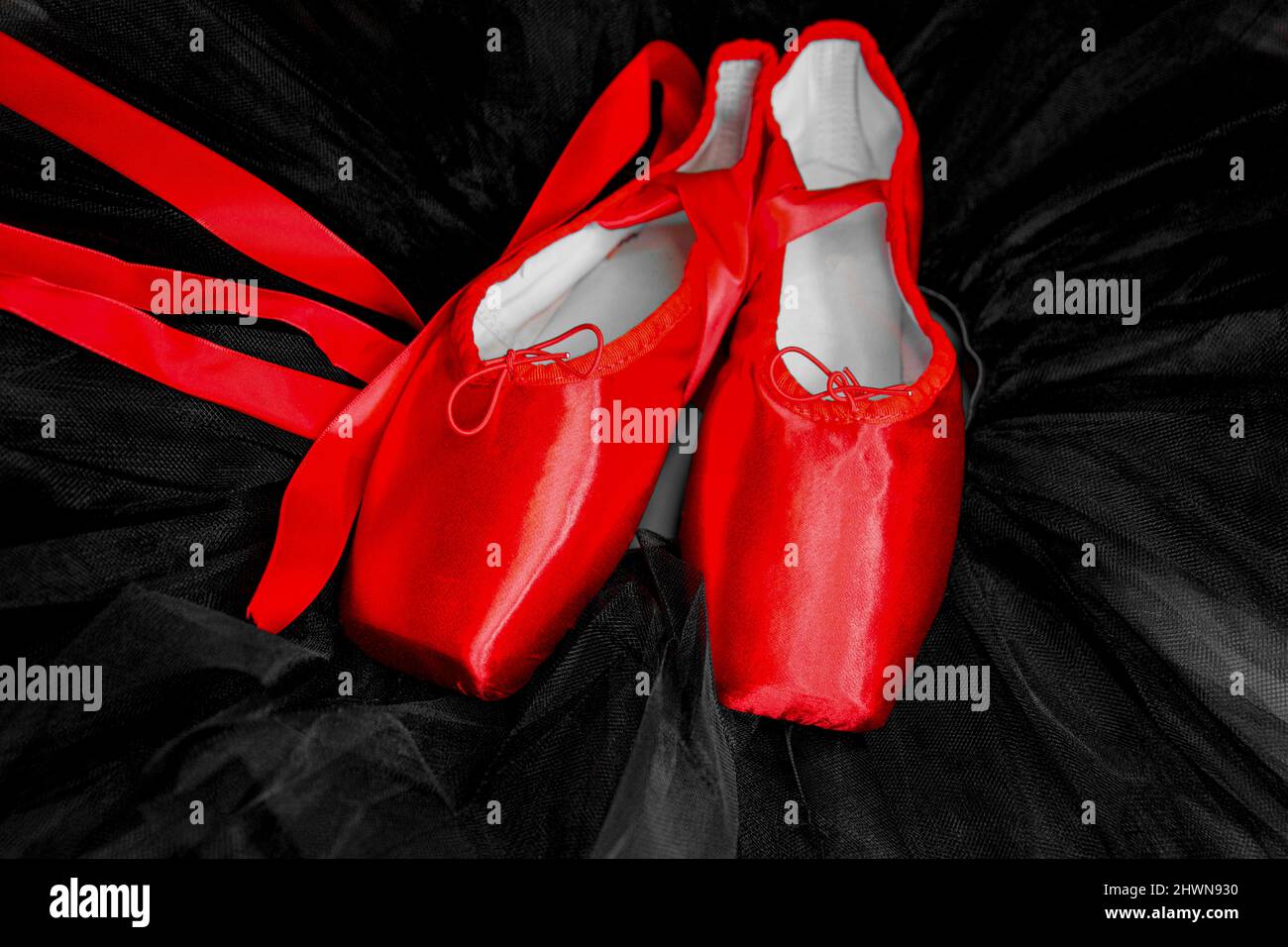 Red ballet pointe shoes set on top of a black tutu. Stock Photo