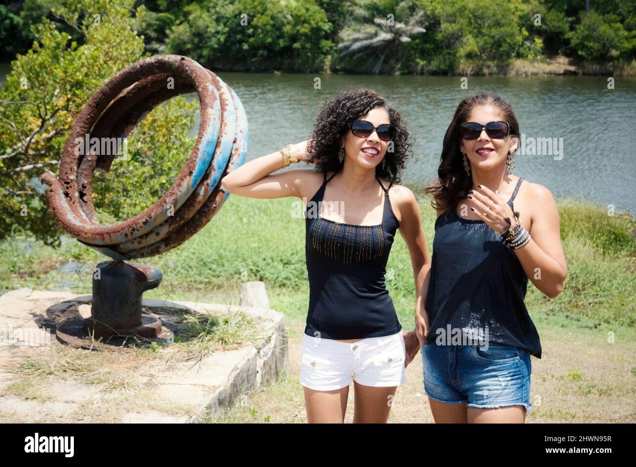 Portrait of two sister women against a river with trees in the background. Salvador, Bahia, Brazil. Stock Photo