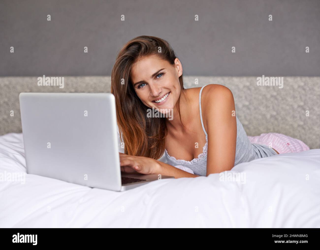 Blogging. Shot of an attractive young woman using her laptop while lying on the bed. Stock Photo