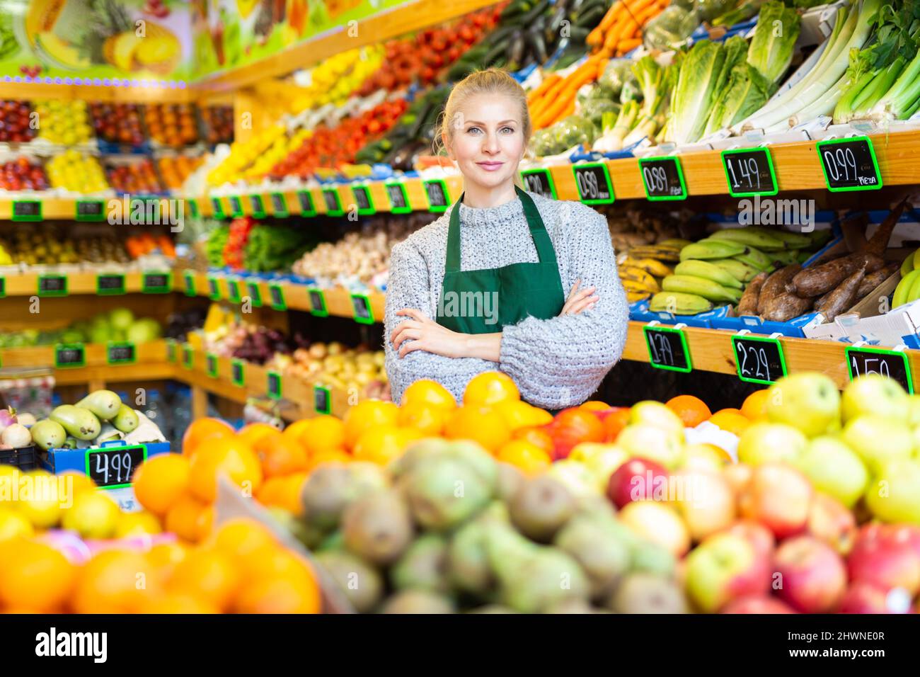 Successful female grocery store owner standing near fruits and