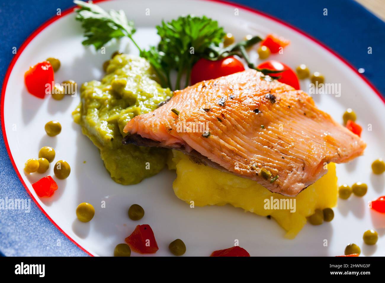Tasty fried trout fillet served mashed potatoes, guacamole and greens on plate Stock Photo