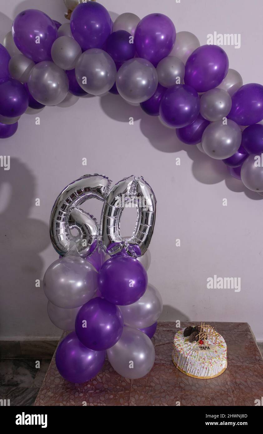 60th birthday decorations with colorful balloons and white cakes from different angle Stock Photo