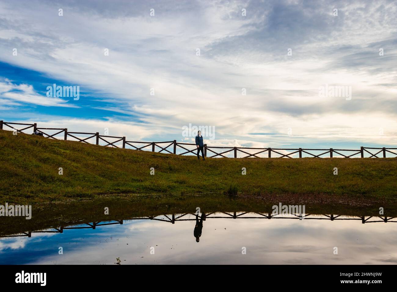 mountain top lake view with dramatic sky and isolated girl with water reflection at morning image is taken at latilum peak shillong meghalaya india. Stock Photo