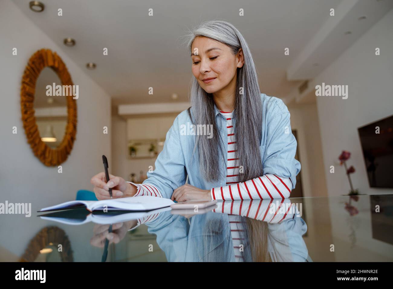 Woman sitting at the table and writing in notebook at home Stock Photo
