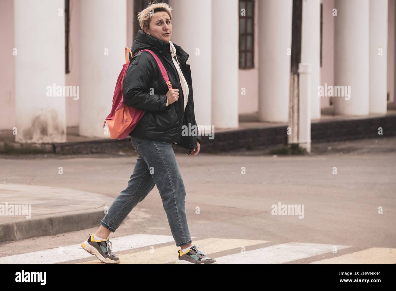 a girl in casual clothes crosses the road through a pedestrian crossing ...