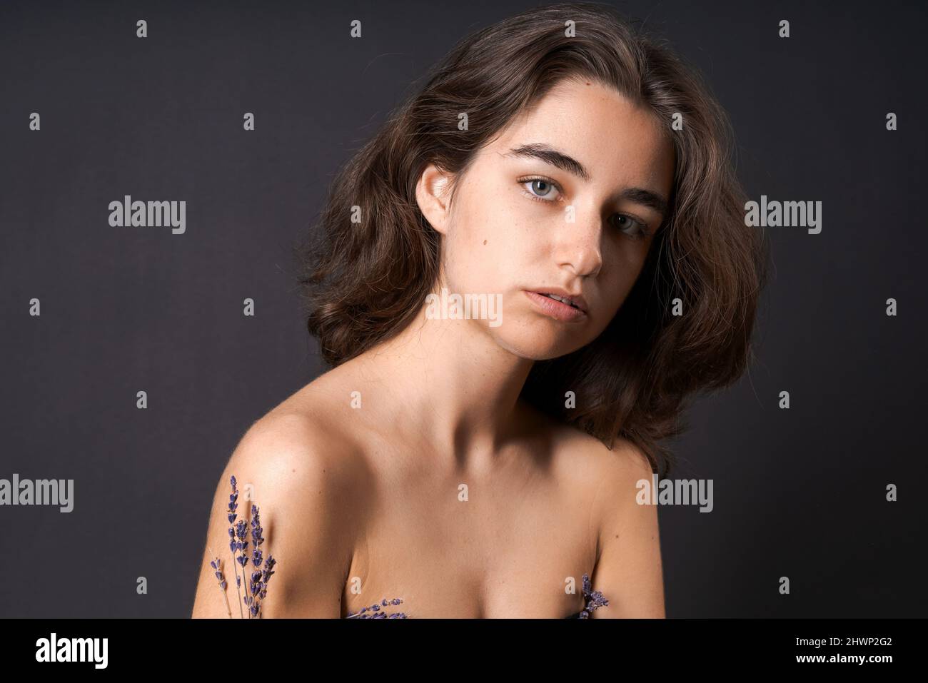Unshaven armpit concept. Girl is holding lavender flowers in front her armpits. Symbol of unshaven body parts. Body positivity and naturalness. Problems home depilation on black background Stock Photo