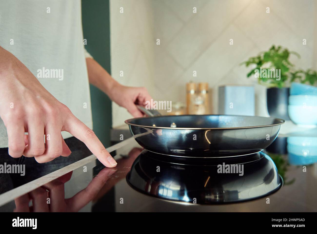 https://c8.alamy.com/comp/2HWP5AD/modern-kitchen-appliance-woman-hand-turn-on-induction-stove-with-steel-frying-pan-finger-touching-sensor-button-on-induction-or-electrical-hob-2HWP5AD.jpg