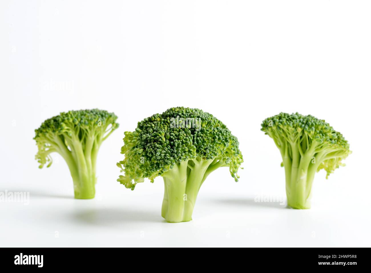 Three sliced and raw broccolis on a white background. Stock Photo