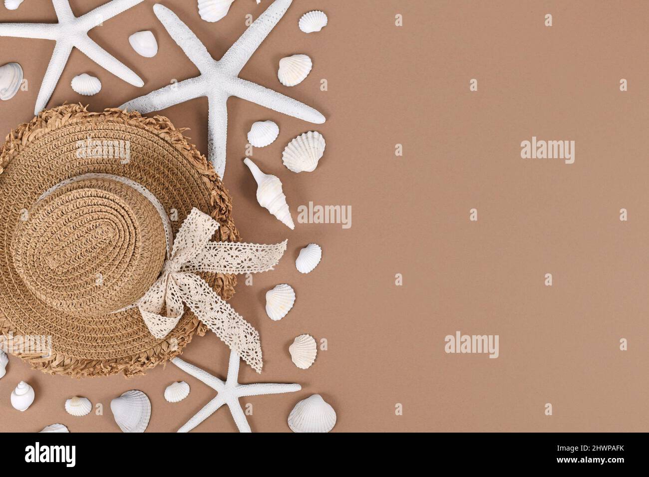 White starfish, seashells and summer straw hat on sand brown background with copy space Stock Photo