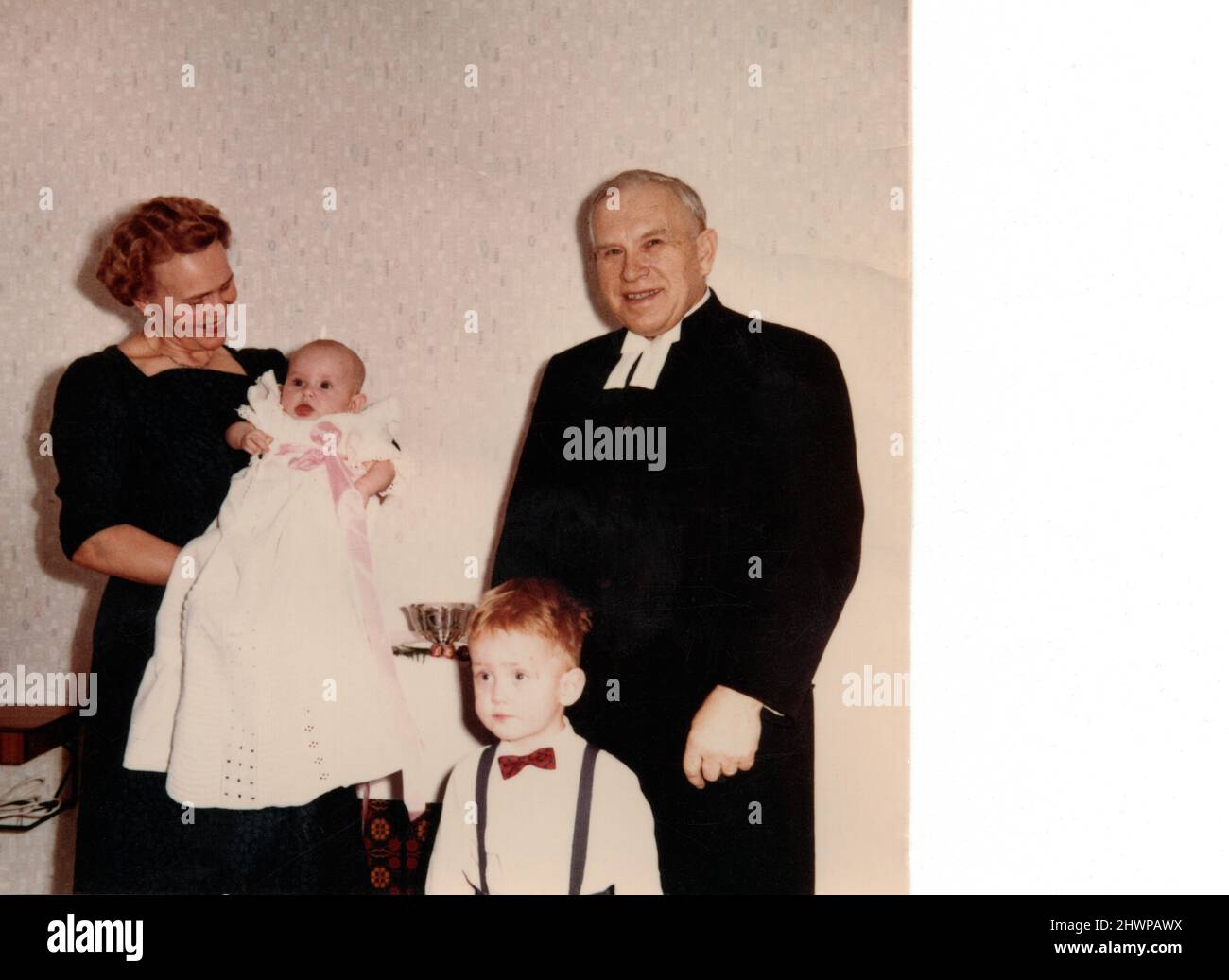 Priest, mother holding baby and small boy in smart clothes, 1960 Sweden. Concept of family, nostalgia, togetherness, yesteryear Stock Photo