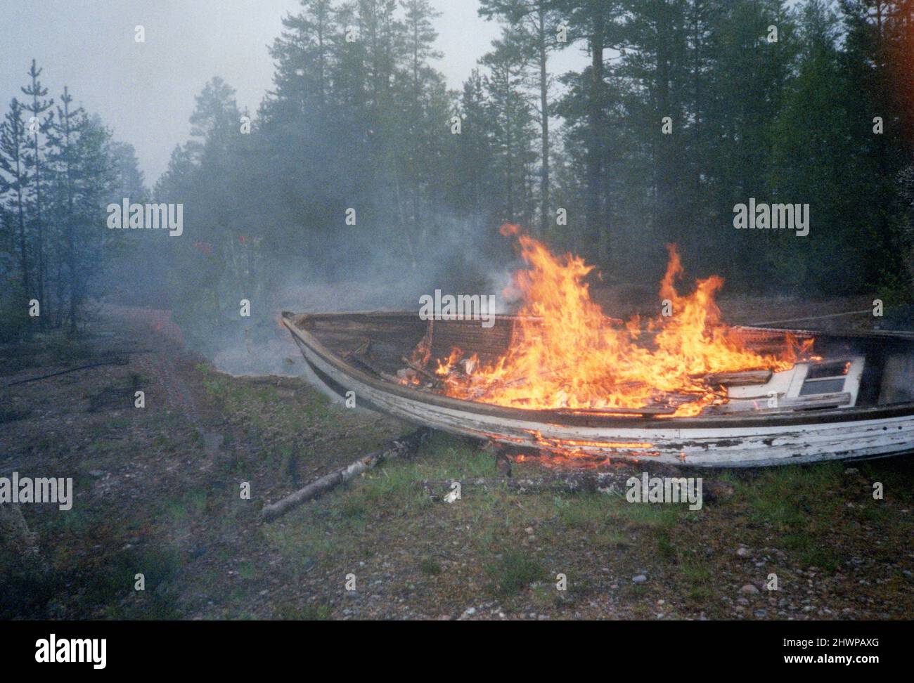 Old dilapidated wooden rowing boat burning on fire in forest, Sweden Stock Photo