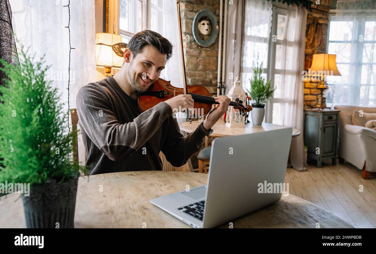 Male music teacher teaching how to play a song the violin online during