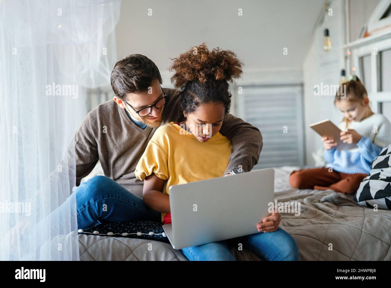 Preteen schoolgirl doing her homework with notebook at home. Child using gadgets to study. Stock Photo