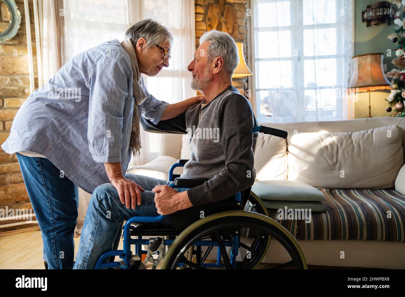 Mature man with disability in wheelchair spending time together with his wife at home Stock Photo