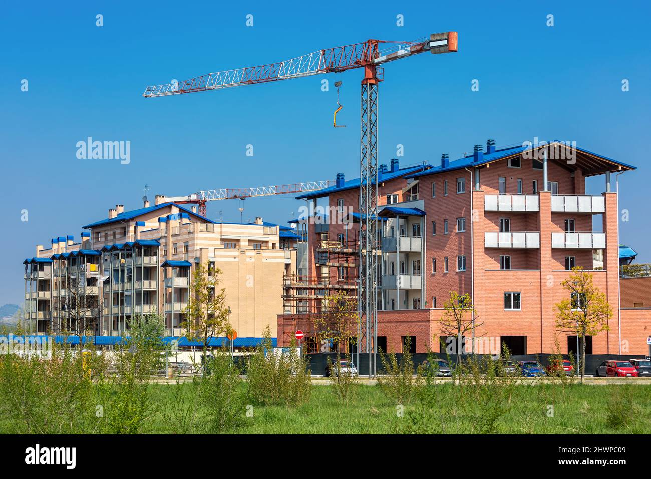Construction cranes and new residential buildings under blue sky in Alba, Piedmont, Northern Italy. Stock Photo