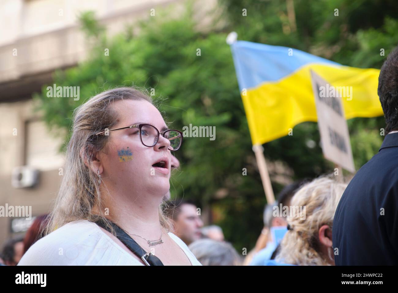 Buenos Aires, Argentina; March 6, 2022: March for peace in Ukraine, against Russian war and invasion. Young woman singing the Ukrainian anthem. Stock Photo