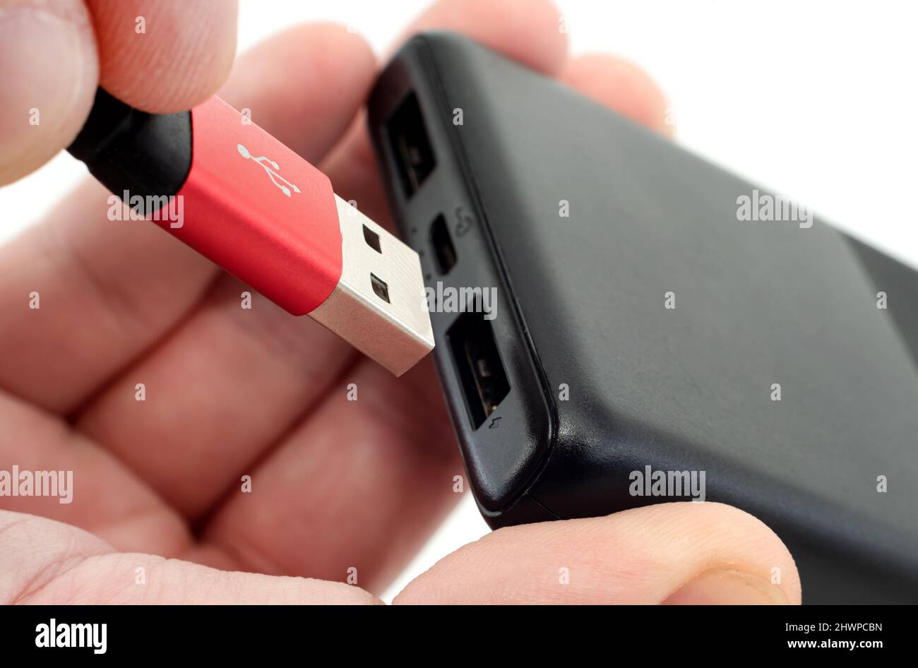 The man's hands hold a USB cable to connect to the battery. USB cable