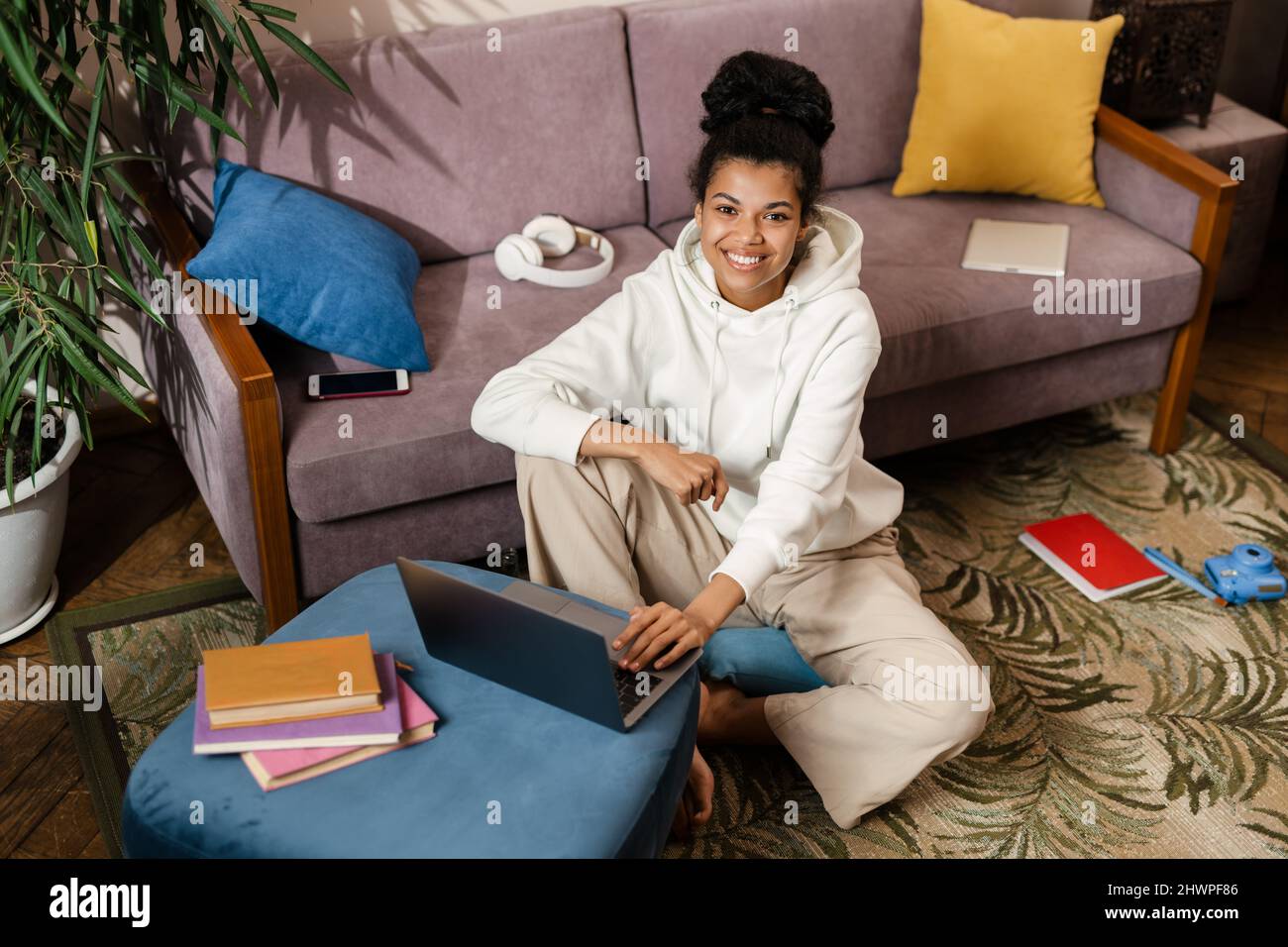 Young black woman using laptop while sitting on floor at home Stock ...