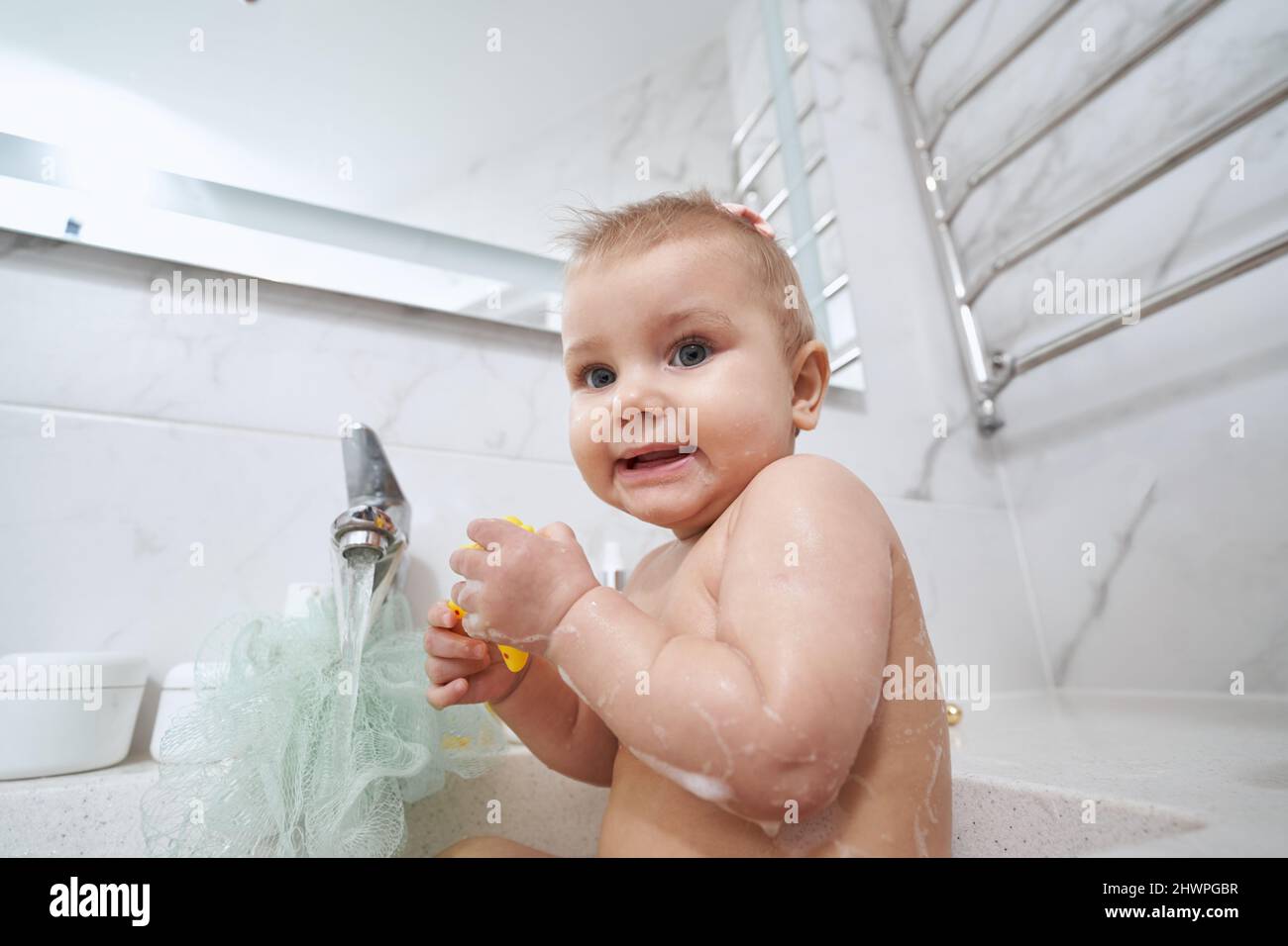Scared baby staring at camera while taking bath Stock Photo Alamy